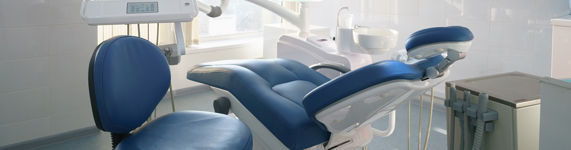 The image shows a modern dental clinic interior with various pieces of equipment, including a dental chair and an X-ray machine.