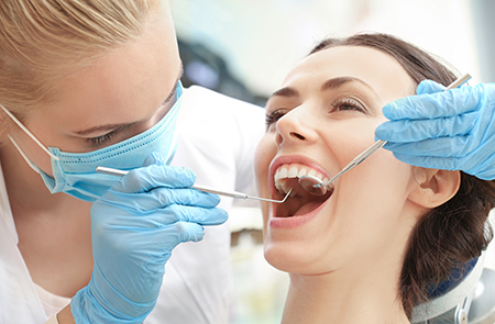 A dental hygienist assisting a patient with a teeth cleaning procedure, using specialized equipment.